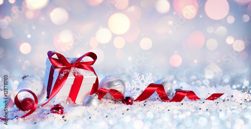 Fotografie, Obraz Gift Box And Baubles On Snow With Shiny Background