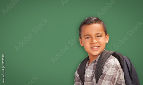 Cute Hispanic Boy with Backpack In Front of Blank Chalk Board.