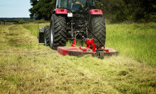 Farming: Large Red Tractor Moving Green Farmers Pasture, Motion Close Up 