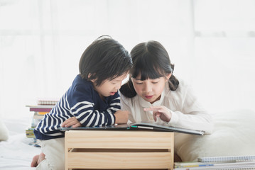 Canvas Print - children reading a book on white bed