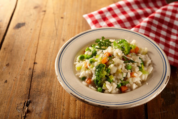 Wall Mural - Bowl of risotto risi bisi and veggies beside checkered napkin