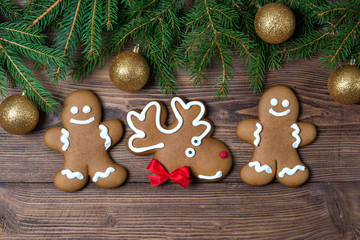 Wall Mural - Christmas gingerbreads on wooden background with fir frame with golden balls, top view