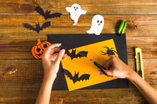 Cuts Of Paper For Halloween. Hand Cut Paper. Ghosts, Pumpkins, Bats, Spider, Witch Green Fingers. Scissors And Stationery Knife. On A Wooden Background. Top View. Flat Lay.