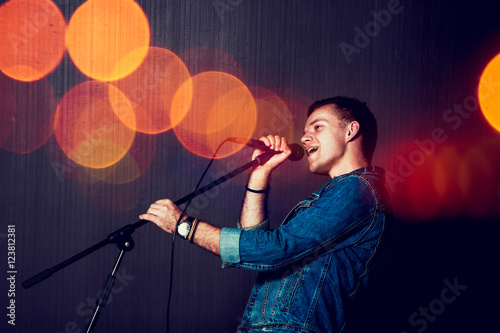 Plakat Młody człowiek śpiewa z mikrofonem.