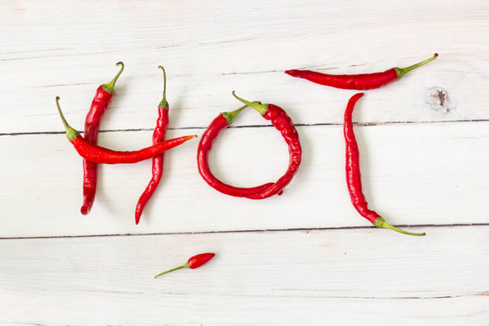 Hot word composed of red hot chili peppers, top view.