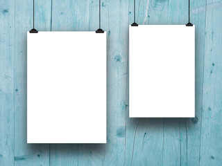 Two blank frames hanged by clips against aqua wooden boards background