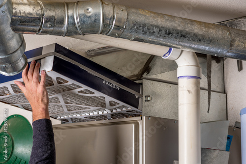 Fotomural Man replaces a filter in a furnace