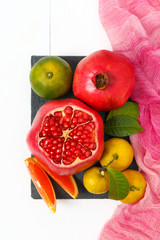 Top view of a set of fruits pomegranate, mandarin, orange on white wooden background