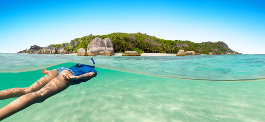 Wall Mural - Young woman snorkling next to tropical island