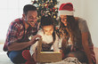 © Tijana - Cute girl opening a magical present on a Christmas morning with her family