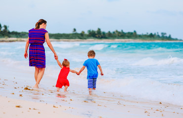 back view of mother and two kids walking on the beach