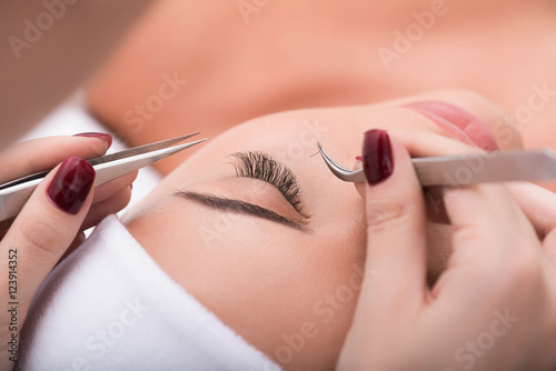 Cuadros en Lienzo Beautiful young woman during eyelash extension