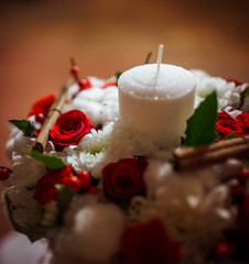 A closeup of white candle standing n the red wreath