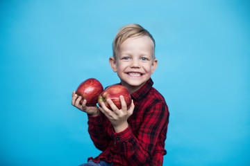 Wall Mural - Handsome little kid with fruits. Studio portrait over blue background