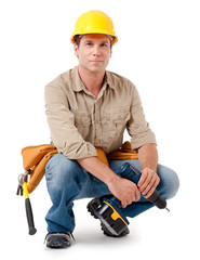 Full-length construction worker contractor carpenter squatting kneeling in hard hat with tools isolated on white background