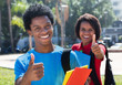 Two happy african american students on campus showing thumbs
