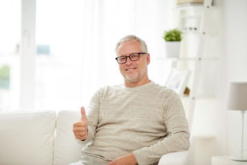 Wall Mural - smiling senior man showing thumbs up at home