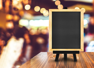 Poster - Blackboard with easel on wood table at blurred coffee shop backg