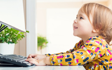 Wall Mural - Happy toddler girl typing on her computer