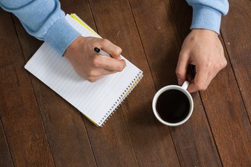 Poster - Man holding a cup of coffee and writing on notepad
