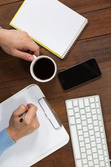Poster - Man writing on clipboard while having cup of coffee