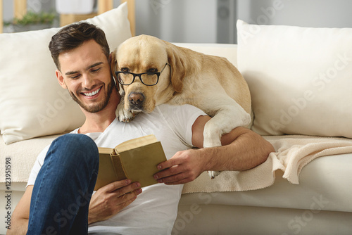 Fotografía handsome guy holding book while smart pet read it
