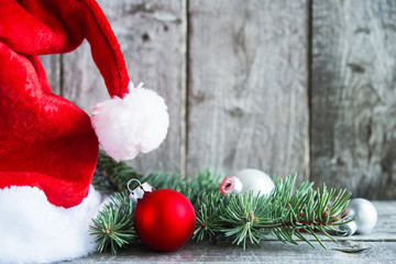 Wall Mural - santa claus hat and red and silver christmas decorations on rustic wood background. merry christmas 