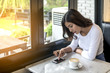 © sunti - Beautiful young woman Playing Mobile with morning coffee