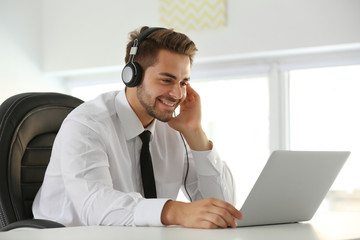 Sticker - Handsome young man listening to music with headphones and working on laptop at office