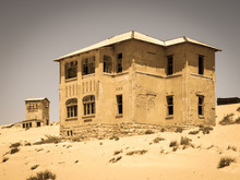 Ghost Buildings Of Old Diamond Mining Town Kolmanskop Near Luderitz In Namibia. Abandoned House Ruins Sunken In The Sand Dunes Of Namib Desert. Vintage Toning Photography.