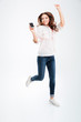 Full length portrait of a woman listening music and jumping