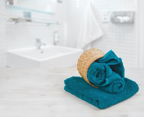 Wall Mural - Green-blue folded towels in wicker basket over defocused bathroom