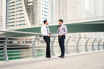 Wall Mural - Two man standing and talking at a promenade in Dubai Marina.