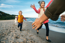 Group Portrait Of Two Funny Smiling Laughing White Caucasian Children Kids Friends Playing Running To Mother Parent Adult On Ocean Sea Beach On Sunset Outdoors, Happy Lifestyle Childhood Concept