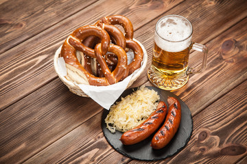 Wall Mural - Pretzels, bratwurst and sauerkraut on wooden table