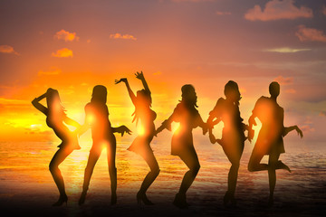 Dancing girls silhouettes against of sunset at the beach