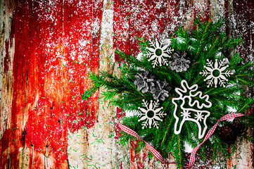 Wall Mural - Christmas fir branches on rustic red wooden background.Vintage Christmas wooden toy in the form of a deer. Handmade wooden snowflakes. Spruce cones. The red ribbon in the cage.