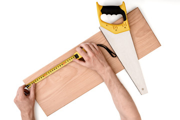 Wall Mural - Close up view of a man's hands measuring wooden plank with tape line, isolated on white background