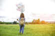© sunti - Young beautiful woman with colorful balloons on a green meadow