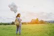 © sunti - Young beautiful woman with colorful balloons on a green meadow