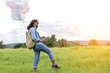 © sunti - Happy young beautiful woman with colorful balloons in the grass