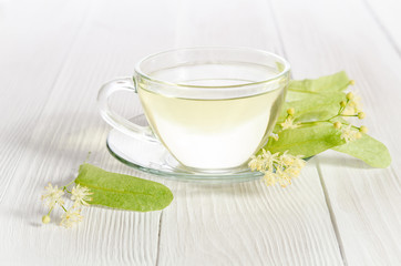 Glass cup of tea with linden on white wooden table