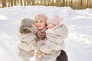 Portrait of two little daughters with mother in a beige warm clothes in winter