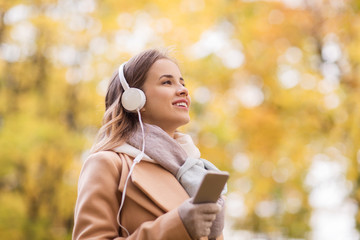 Poster - woman with smartphone and earphones in autumn park