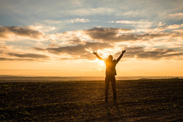 Businessman Raising Arms for Success at the Field on sunset