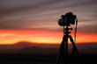 © Designpics - Camera set on a tripod aimed at a silhouette of a landscape during sunset
