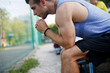 © snedorez - Fitness guy resting after workout on bench in street stadium