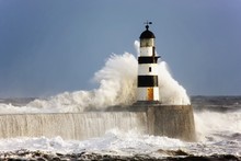 Seaham, Teesside, England; Waves Crashing Against A Lighthouse