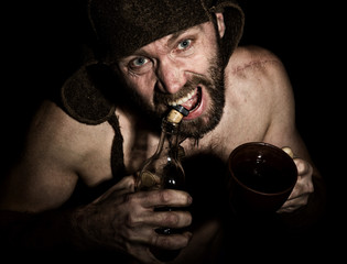 Wall Mural - Dark portrait of scary evil sinister bearded man with smirk, he opens a bottle of brandy his teeth . strange Russian man with a naked torso and a woolen hat