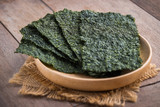 Fototapeta  - Crispy dried seaweed on wooden plate